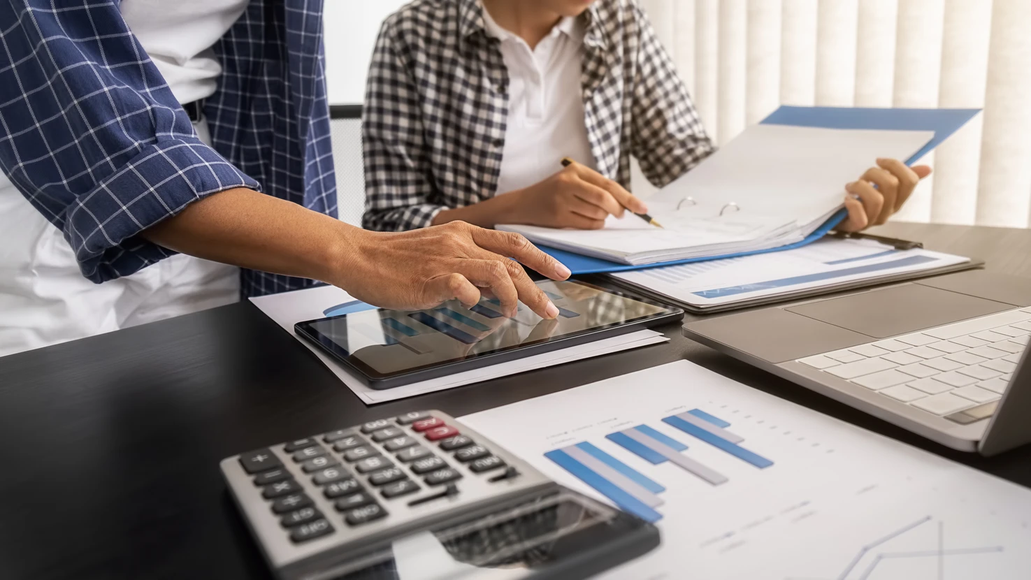 Deux professionnels en tenue d'affaires analysent des données financières dans un bureau moderne