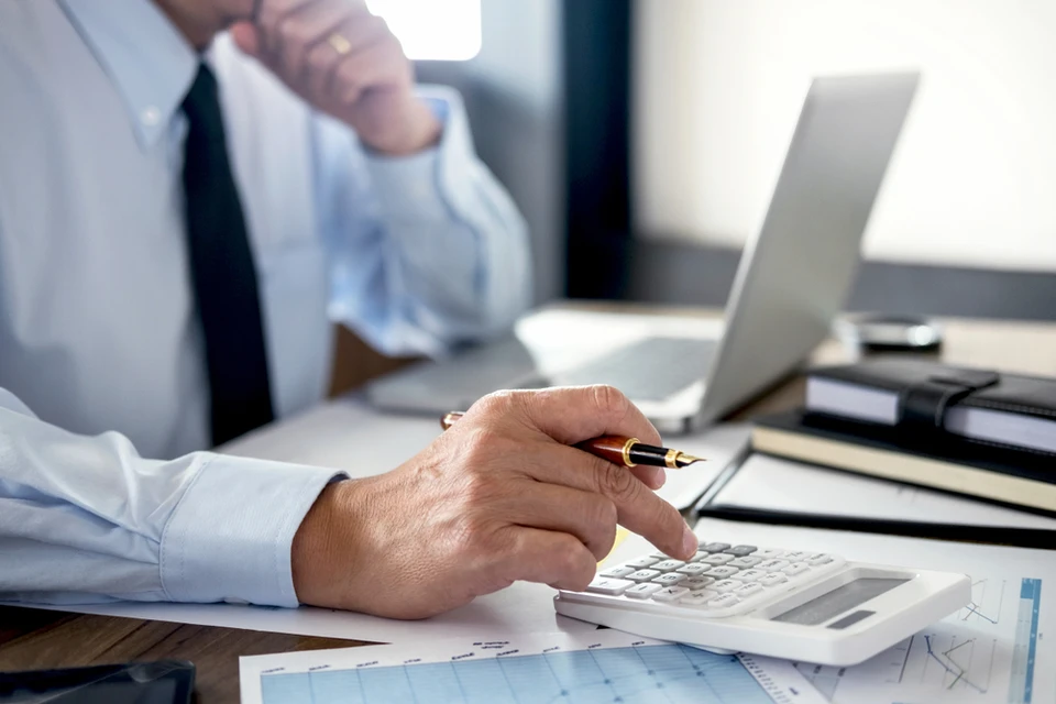 R&eacute;union de travail en int&eacute;rieur avec trois personnes analysant des rapports financiers sur table en bois