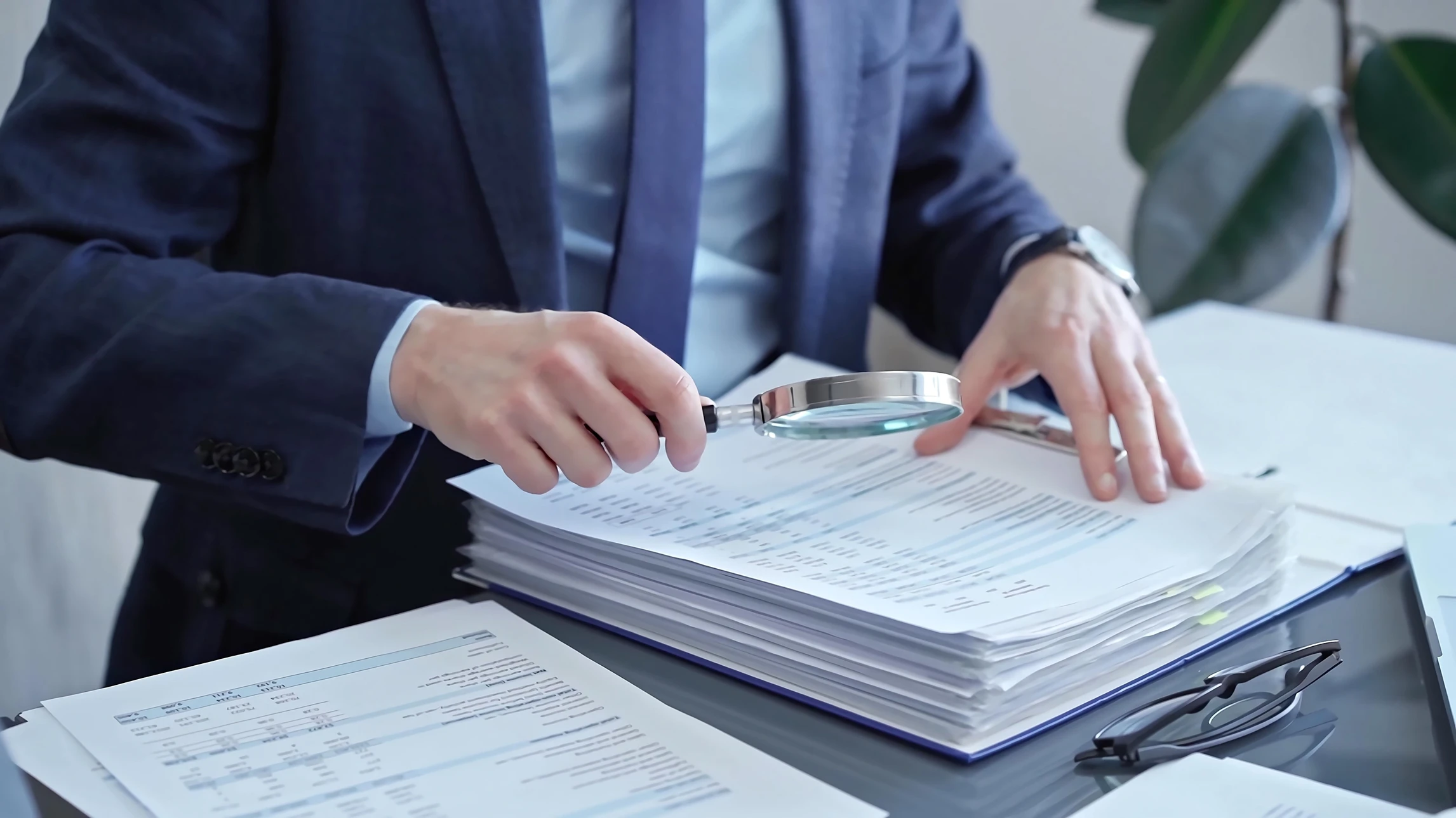 Espace de travail intérieur avec professionnel analysant des rapports financiers sur table en bois